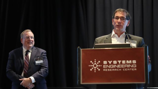 Two men in suits standing by a podium